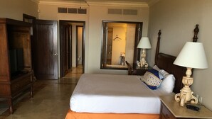 Ein Hotelzimmer mit einem großen Bett, einem Schminktisch, einem Spiegel und einem Schreibtisch mit einer Lampe.