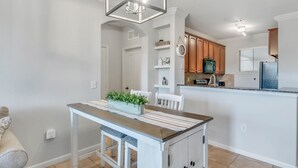 Una cocina moderna con armarios blancos, una mesa de comedor de madera y una isla integrada con un lavamanos.