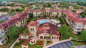 Un gran complejo turístico con varias edificaciones, una piscina central y jardines ajardinados.