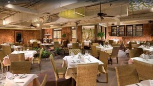 Un restaurante con varias mesas y sillas, algunas con manteles blancos y otras sin mantel.