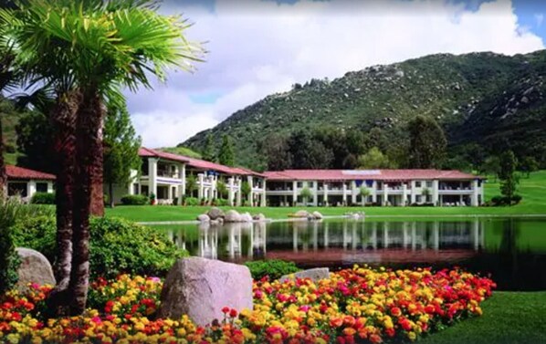 Un resort con varias edificaciones, un lago y montañas al fondo.