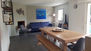 Una sala de estar moderna con una mesa de comedor de madera, un sofá azul y una chimenea.