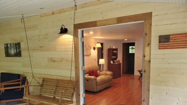 A wooden interior with a swing chair, a sofa, and a wooden floor. - Mountain Laurel Cottage ~ Bat Cave North Carolina  RELAX, REFRESH, RENEW! (Hendersonville)