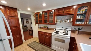 A kitchen with wooden cabinets, a stove, and a refrigerator. - Mountain Laurel Cottage ~ Bat Cave North Carolina  RELAX, REFRESH, RENEW! (Hendersonville)