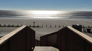 Una pasarela de madera que conduce a una playa con vista despejada al océano.