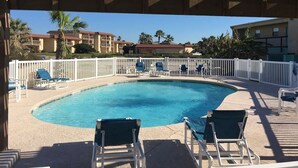 Un área de piscina con sillones de descanso y una valla blanca.