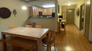 Un comedor amplio con una gran mesa de madera y sillas, una cocina al fondo y un pasillo que lleva a otras habitaciones.
