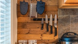 A kitchen with wooden walls, hanging kitchen tools, and a coffee maker. - Cedar Blossom Bungalow - Pet friendly getaway with a 5 min walk to downtown (Hot Springs)