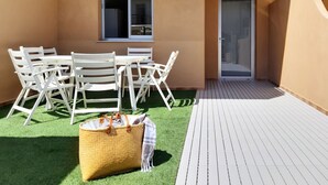 Une terrasse avec une table et des chaises, une porte et une fenêtre.