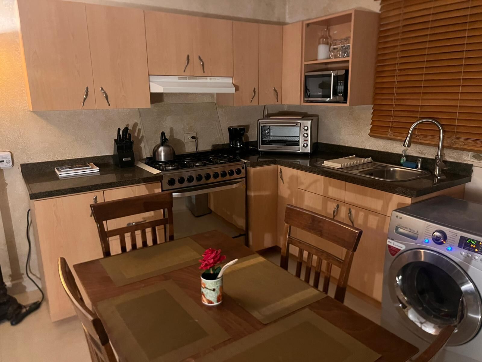 Uma cozinha compacta com fogão, forno, micro-ondas e máquina de lavar.