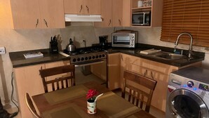 A compact kitchen with a stove, oven, microwave, and a washing machine. - Aruba Sun, Sand & Beach  Apartment 5 min from Beach. (Sanicolas)