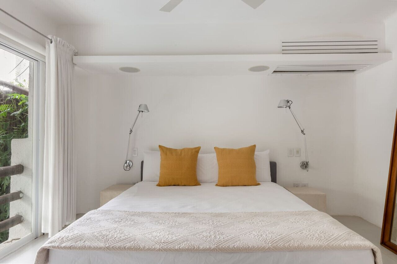 Un dormitorio con una cama grande, dos lámparas de noche y una ventana con cortinas.
