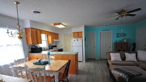A kitchen with wooden cabinets, a dining table with chairs, a refrigerator, and a ceiling fan. - Welcome to Bayside Breeze! One Block From Town Beach, Walk to Waterfront Dining (Rock Hall)