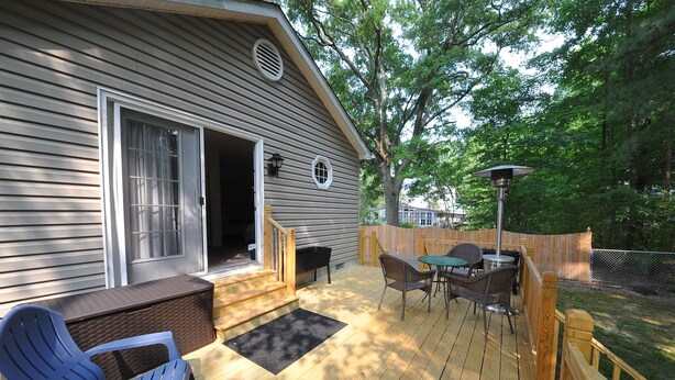 A deck with a table and chairs, a blue chair, a bench, and a wooden fence. - Welcome to Bayside Breeze! One Block From Town Beach, Walk to Waterfront Dining (Rock Hall)