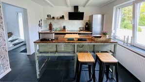 Una cocina moderna con una isla central, horno empotrado y un amplio ventanal que proporciona luz natural.