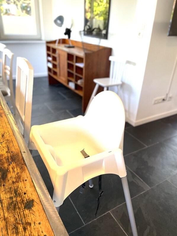 A modern kitchen with a wooden countertop, a white chair, and a white cabinet.