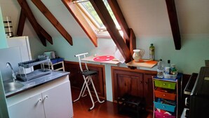 Et lille køkken med ovenlys, en vask, et bord og en stol.