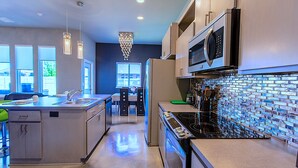 Una cocina moderna con una isla central, electrodomésticos de acero inoxidable y un salpicadero de azulejos azules.