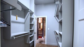 Un pasillo estrecho con estanterías empotradas a ambos lados, que conduce a una habitación con una puerta al final.