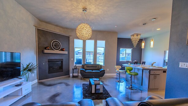 Una sala de estar moderna con chimenea, televisión y comedor con taburetes de bar.