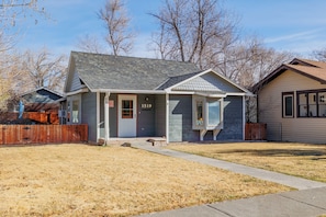 A single-story house with a grey roof, a front door, and a mailbox.