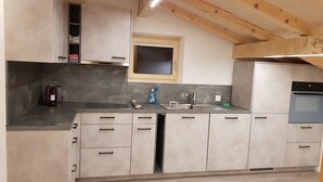 A modern kitchen with grey cabinets, a stainless steel sink, and a built-in oven. - Lischa 3. OG Süd by Interhome (Fiesch)
