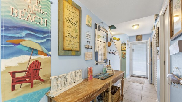Un couloir agrémenté d’une console en bois, d’une fresque murale sur le thème de la plage et de divers éléments décoratifs.