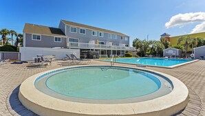 Une piscine avec des chaises longues et un bâtiment doté d’un balcon en arrière-plan.