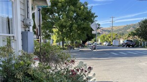 Une rue résidentielle bordée de maisons, avec un arbre et des véhicules garés.