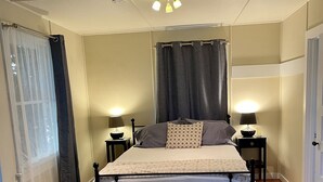 Une chambre à coucher comprenant un lit, des tables de chevet, un banc et un luminaire au plafond.
