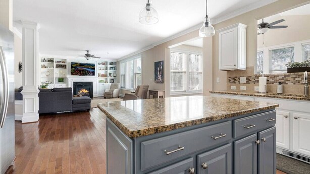 A spacious kitchen with a granite island, white cabinetry, and a built-in oven.