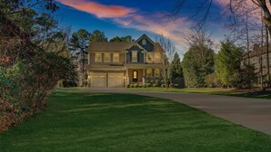 A two-story house with a garage, surrounded by a well-maintained lawn and trees.