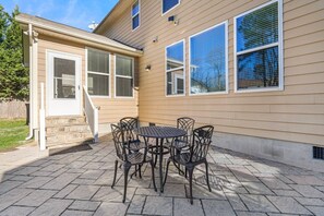 A patio with a stone floor, a round table, and four chairs.