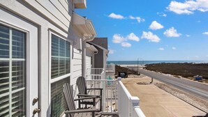 Eine Strandimmobilie mit Balkon, Sitzgelegenheit im Freien und Blick auf Strand und Meer.