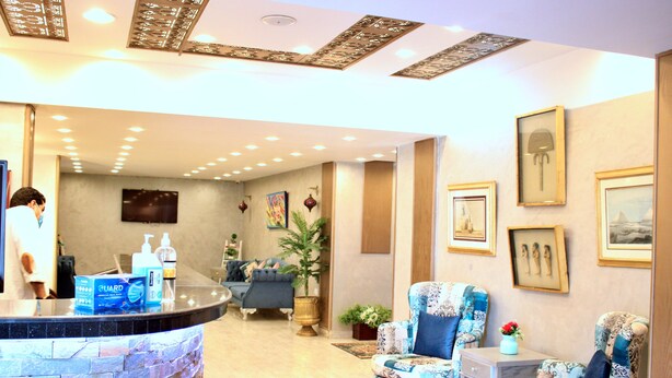 Un vestíbulo de hotel con mostrador de recepción, zona de estar y decoración mural.