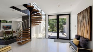 Un interior moderno con una escalera de caracol, un ventanal grande y un sofá.