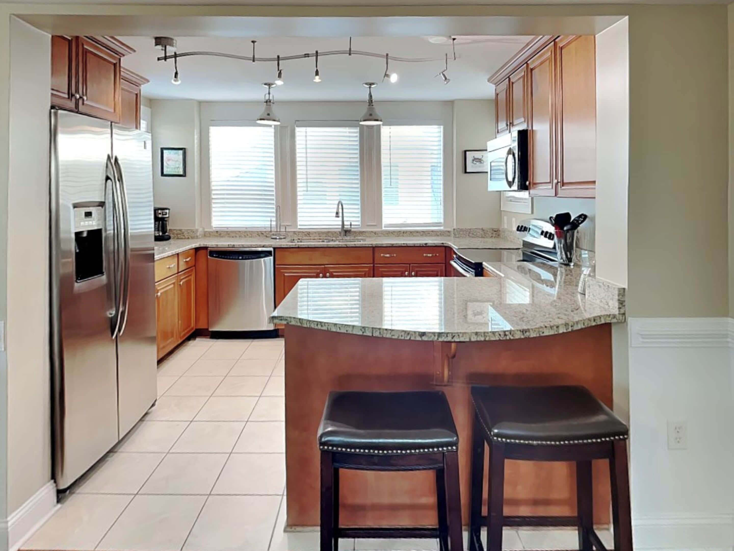 Una cocina moderna con una isla central, electrodomésticos de acero inoxidable y armarios de madera.