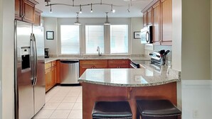 A modern kitchen with a central island, stainless steel appliances, and wooden cabinets.