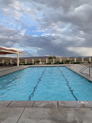 A swimming pool with a 4 ft depth sign, surrounded by a fence and chairs, under a cloudy sky.