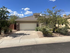 A residential house with a garage, a driveway, and landscaping.