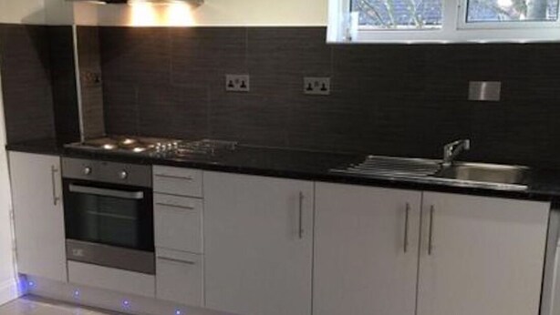 A modern kitchen with a stove, oven, and sink, a window above the sink, and a tiled floor. - Small Modern Comfortable 2 Bedroom Apartment - cmyr (Hayes)