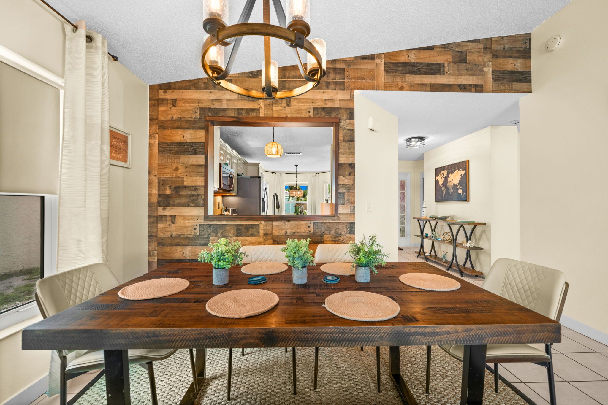 A dining room with a wooden table, chairs, and potted plants.