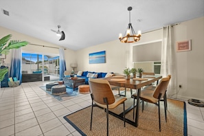 A spacious living area with a dining table, chairs, and a ceiling fan.