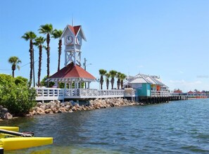 Un bâtiment situé au bord de l’eau, doté d’un clocher, d’une zone abritée pour les bateaux et de plusieurs palmiers.