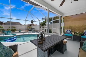 An outdoor patio with a pool, lounge chairs, and a table.