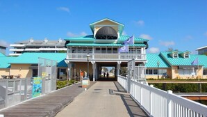 Une jetée mène à un bâtiment doté d’un toit végétalisé et d’un balcon, lequel est entouré d’autres bâtiments aux toits similaires.