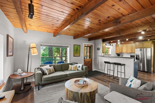 A modern kitchen with stainless steel appliances, a bar area, and a cozy living space with a wooden ceiling.