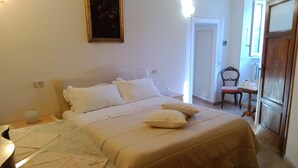 Un dormitorio con cama, mesita de noche, lámpara y una puerta que da a otra habitación.