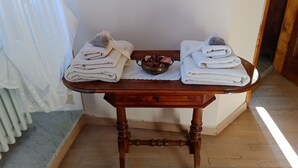 Una mesa de madera con dos pilas de toallas dobladas y un cuenco de sales de baño.