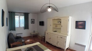 A compact living space with a dining table, a sofa, a cabinet with shelves, a TV, and a ceiling light fixture. - Self-catering cottage 400m from the beach, run by olive growers (Six-Fours-les-Plages)